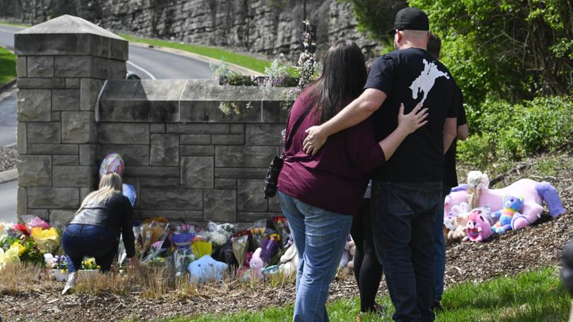 People gather at an entry to Covenant School which has become a memorial for shooting victims.