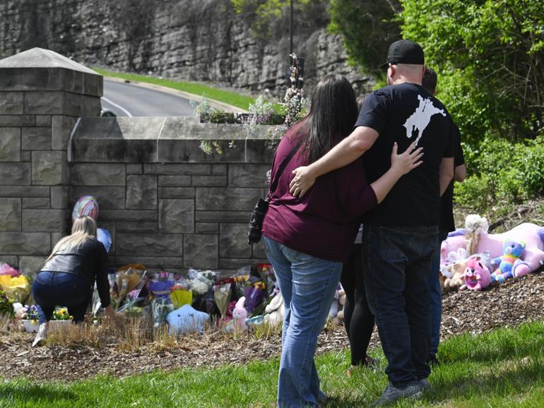 People gather at an entry to Covenant School which has become a memorial for shooting victims.