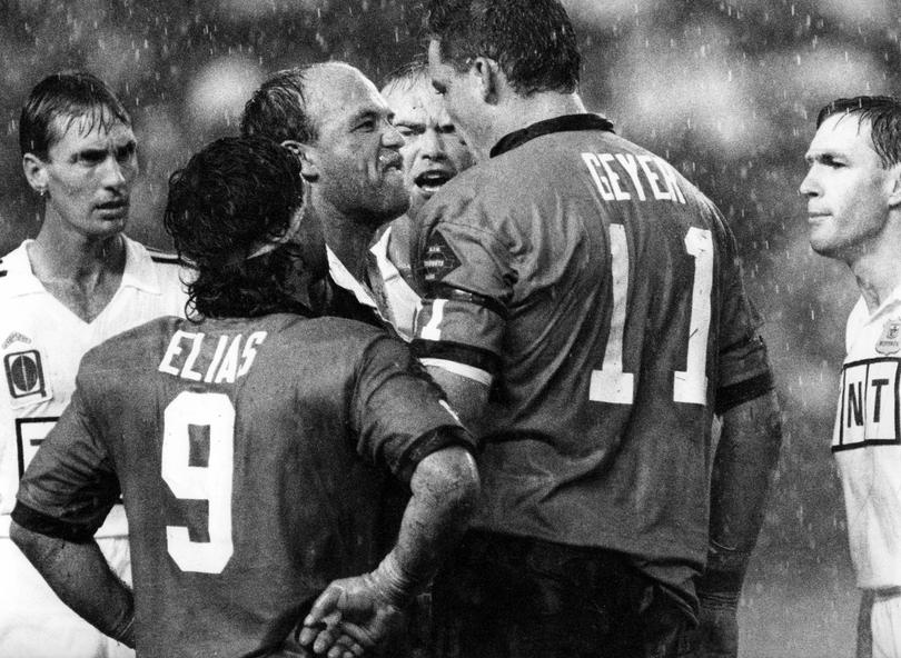 QLD's Wally Lewis and NSW's Mark Geyer, with NSW captain Benny Elias and referee David Manson looking on, argue in torrential rain. 