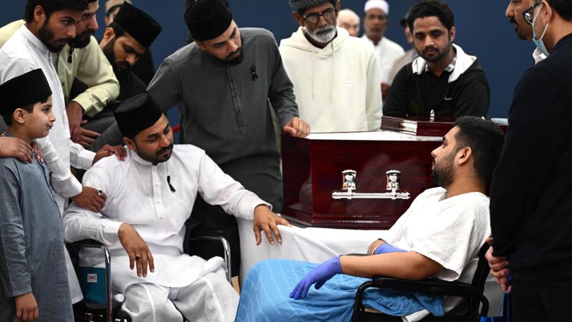 Injured Bondi Junction security guard Muhammad Taha (right) speaks with eldest brother Muzafar Ahmad Tahir (seated, left) and family as he pays his respects at the viewing ahead of the funeral for Faraz Tahir.