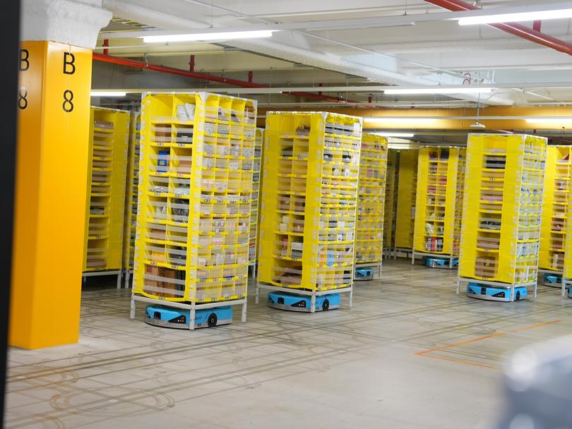The small blue robots move shelves around the warehouse floor and take them to designated collectors.
