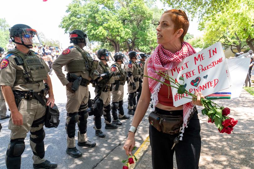 A pro-Palestinian demomstrator walks past Texas State troopers at the University of Texas in Austin, Texas.