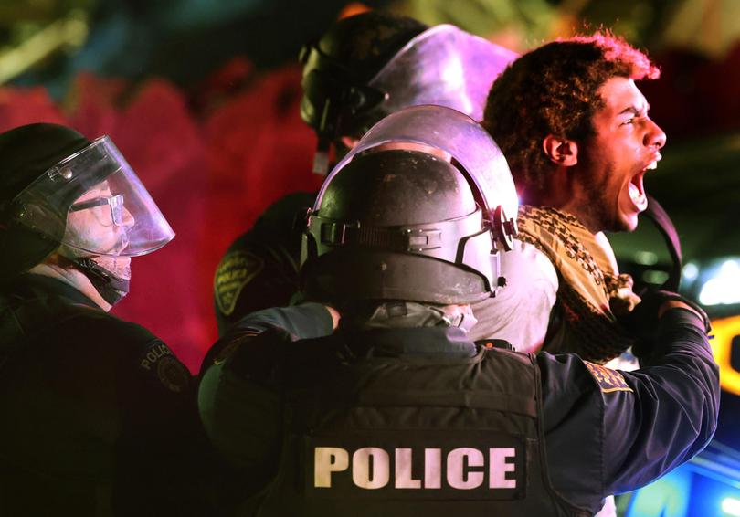 Tucson Police take a protester into custody on Park Avenue as law enforcement personnel from several area agencies clear an encampment of pro-Palestinian protesters from the University of Arizona campus.