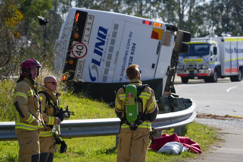 Emergency crews stand near a bus that rolled onto its side near Greta in the Hunter Valley, north of Sydney, Australia, Monday, June 12, 2023. The bus carrying wedding guests rolled over on a foggy night in Australia's wine country, killing and injuring multiple people, police said. (AP Photo/Mark Baker)