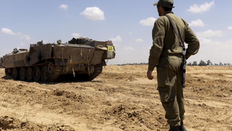 An Israeli soldier walks near an armoured personnel carrier near the border with the southern Gaza Strip.