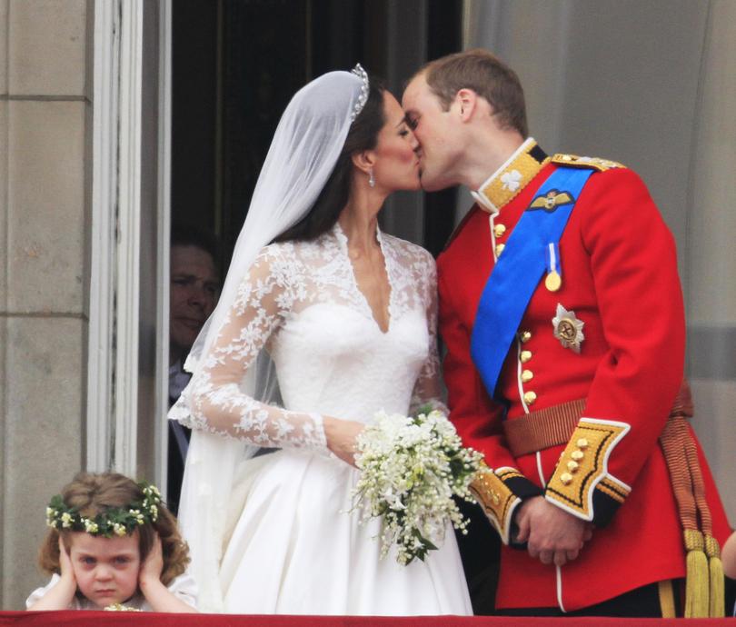 As bridesmaid Grace van Cutsem, left, covers her ears, Britain's Prince William kisses his wife Kate, Duchess of Cambridge, on the balcony of Buckingham Palace after the Royal Wedding in London Friday, April, 29, 2011.  (AP Photo/Matt Dunham)