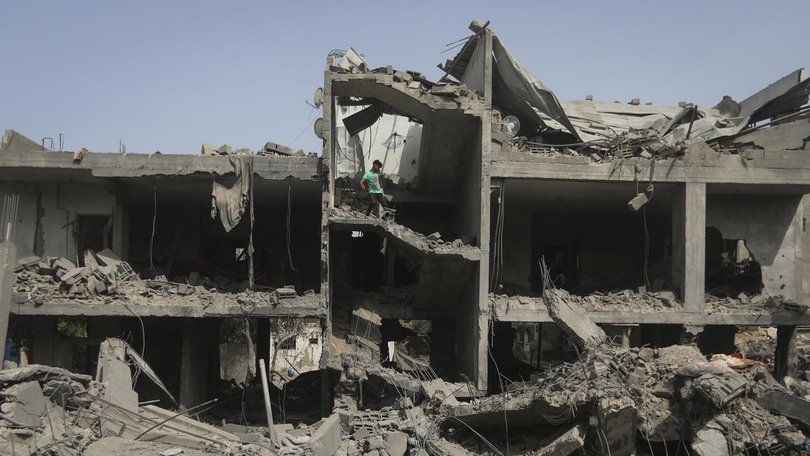 Palestinians look at the destruction after an Israeli strike on a building in Nuseirat camp, Gaza. (AP PHOTO)