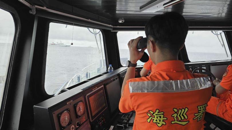 A Taiwanese Coast Guard member monitors a Chinese navy ship near the north of Taiwan. 