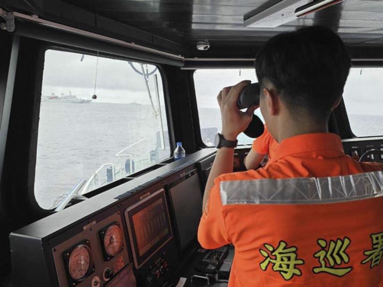 A Taiwanese Coast Guard member monitors a Chinese navy ship near the north of Taiwan. 