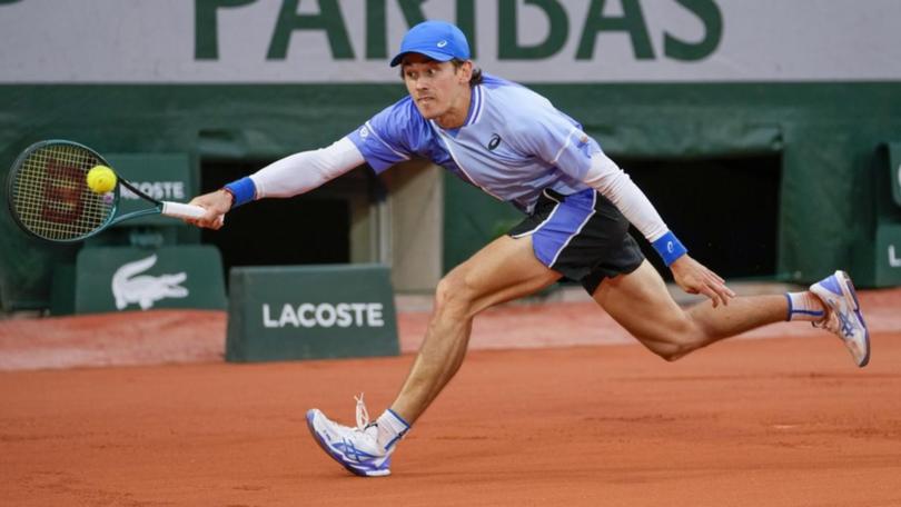Alex de Minaur produced a virtuoso display on wet clay to power into the French Open second round.