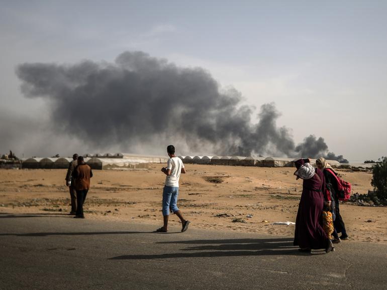 Palestinians walk past after tents in Al-Mawasi, previously declared as a 'safe zone' by Israel, burn in the city of Rafah.