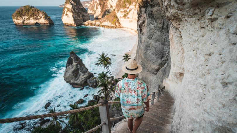 Young Asian traveller walking down to Diamond beach in a morning sunrise in summer season. Nusa Penida island near Bali island, Indonesia, Asia