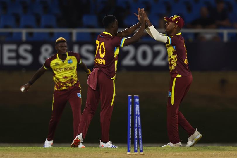 Shamar Joseph and Akeal Hosein of West Indies celebrate the wicket of David Warner.