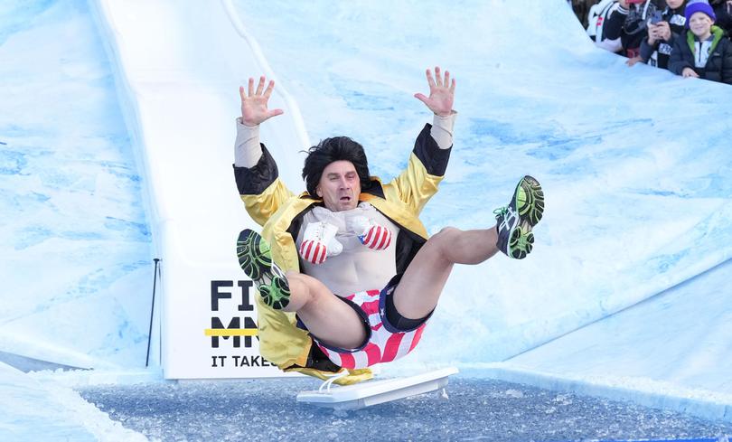 Justin Langer goes down the Freeze MND slide at the MCG in 2022.