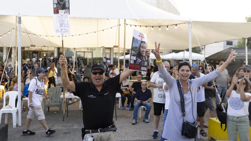 People celebrate as they hold photos of released hostages Noa Argamani and Almog Meir Jan at Tel Aviv's square.