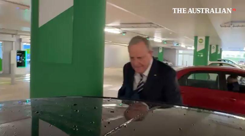 Nine chairman Peter Costello has pushed a journalist to the ground at Canberra Airport.