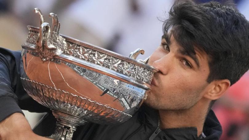 Carlos Alcaraz kisses the trophy after winning the French Open, his third grand slam triumph.