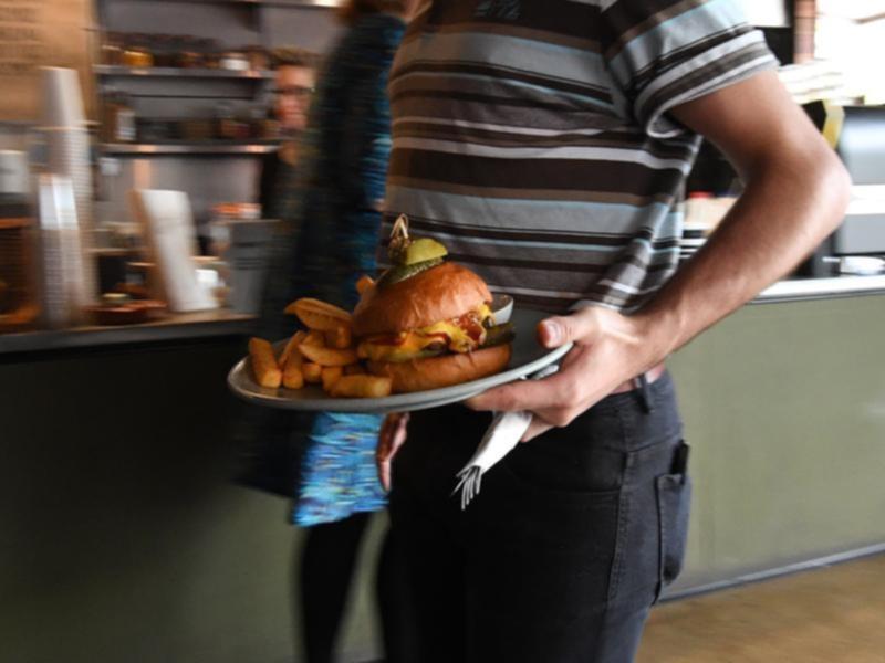 A waiter carries a burger.