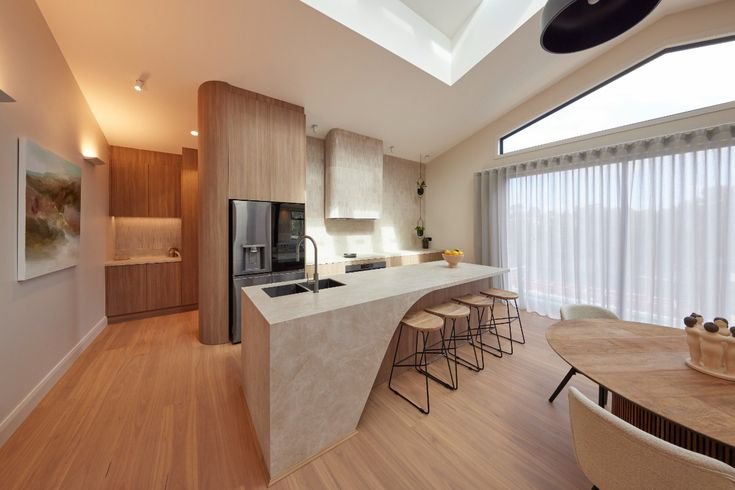 A very tired laminate kitchen was done away with for a sleek stone and timber space with a huge island bench in the Watsonia home.