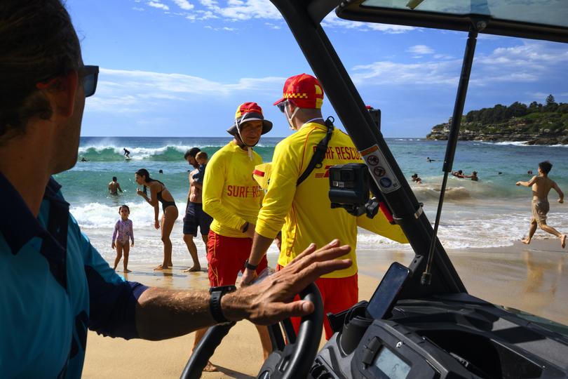 Lifeguards, in blue, and lifesavers, in red and yellow, work to keep beach visitors safe on Bondi Beach. 