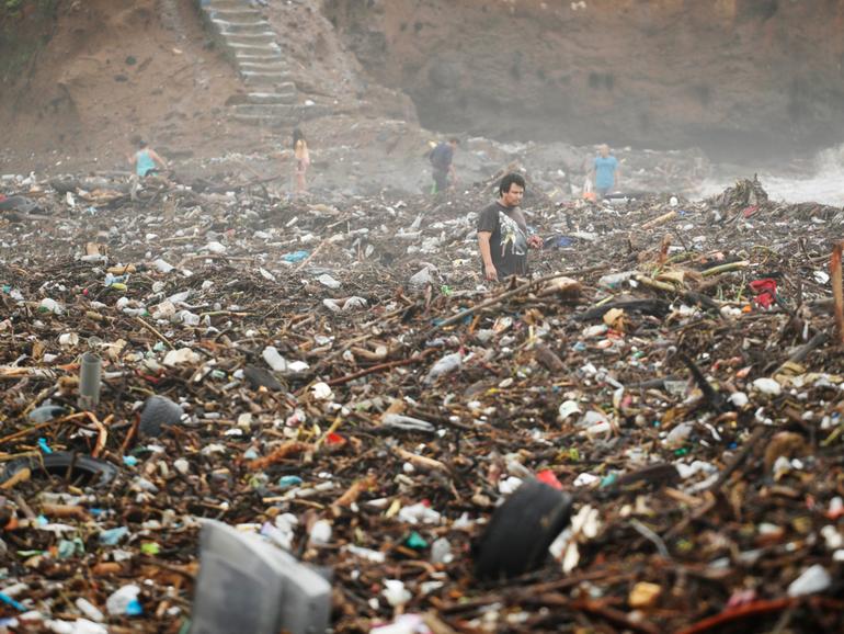 People search for recyclable items in garbage debris in a flooded river in Metalio, El Salvador.