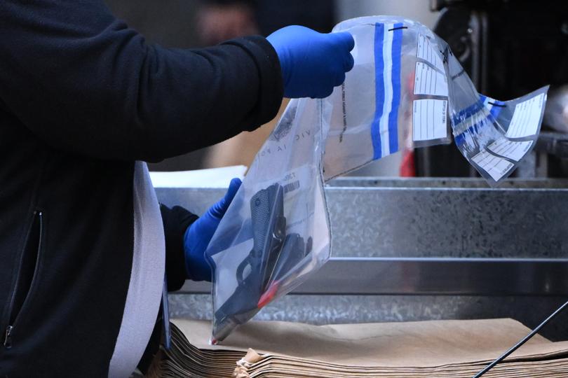 A Victoria Police officer puts a handgun found during a vehicle search into an evidence bag.