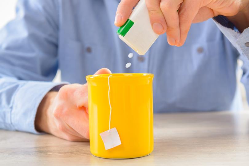 Artificial sweetener being poured into cup of tea