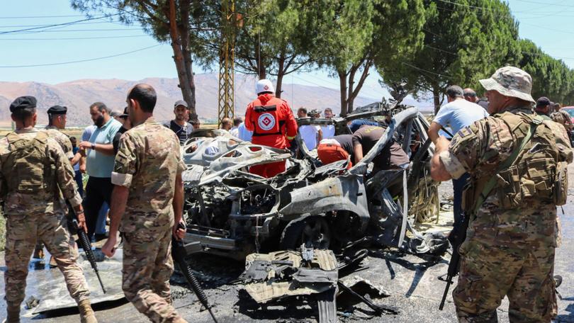 Emergency service members gather around a car destroyed in an Israeli strike targeting a Jamaa Islamiya member in in Lebanon's Western Bekaa area on the weekend.