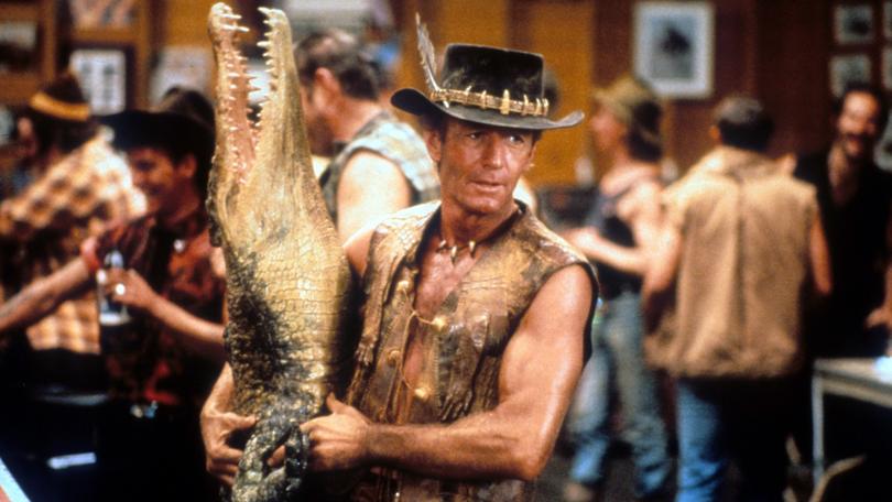 Paul Hogan carrying dead crocodile in bar in a scene from the film 'Crocodile Dundee', 1986. (Photo by Paramount/Getty Images)