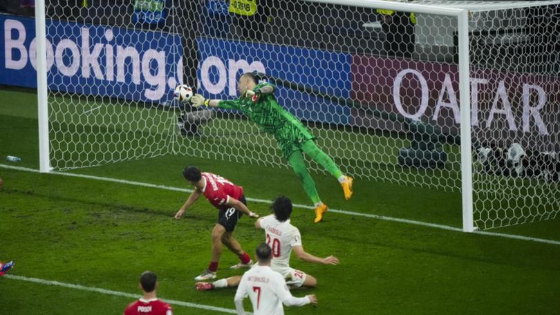 Turkey goalkeeper Mert Gunok leaps to his right to claw away Christoph Baumgartner's (19) header. (AP PHOTO)