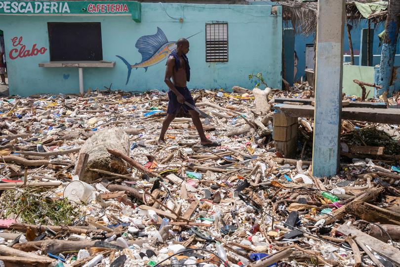A man walks along the beach of Manresa, covered with garbage after the passage of Hurricane Beryl, in Santo Domingo, Dominican Republic.