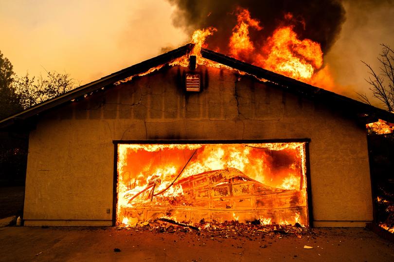 Flames consume a garage as the Thompson Fire burns in California.