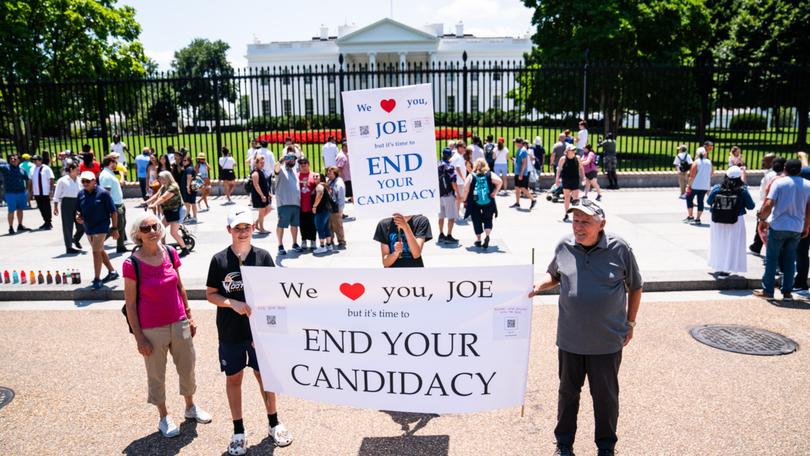 Rebecca Pollack, Micah Pollack, 11, and Mateo Zavala, 14, hold up signs outside the White House on Wednesday calling for Mr Biden to step aside.