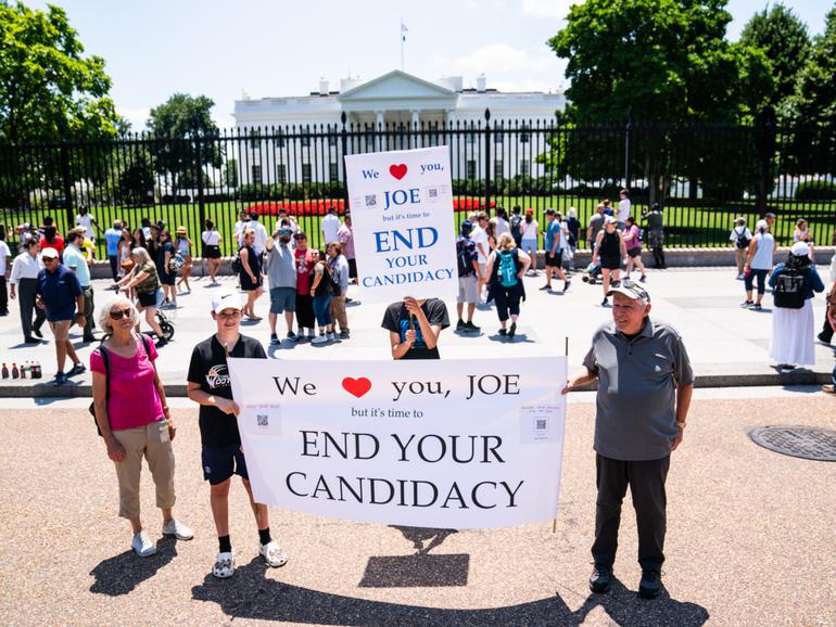 Rebecca Pollack, Micah Pollack, 11, and Mateo Zavala, 14, hold up signs outside the White House on Wednesday calling for Mr Biden to step aside.