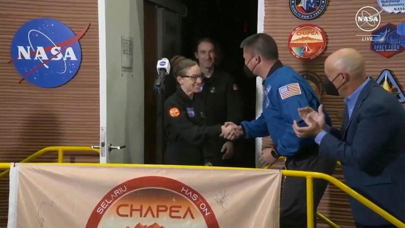 Kelly Haston, centre, a crew member on the first CHAPEA mission, shakes hands with NASA Deputy Director Flight Missions Kjell Lindgren after emerging from their craft.