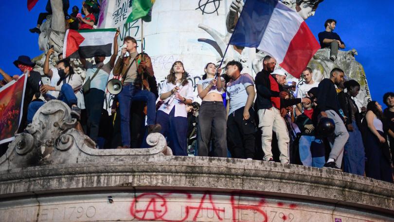 Participants gather during an election night rally following the first results of the second round of France's legislative election at Place de la Republique in Paris.