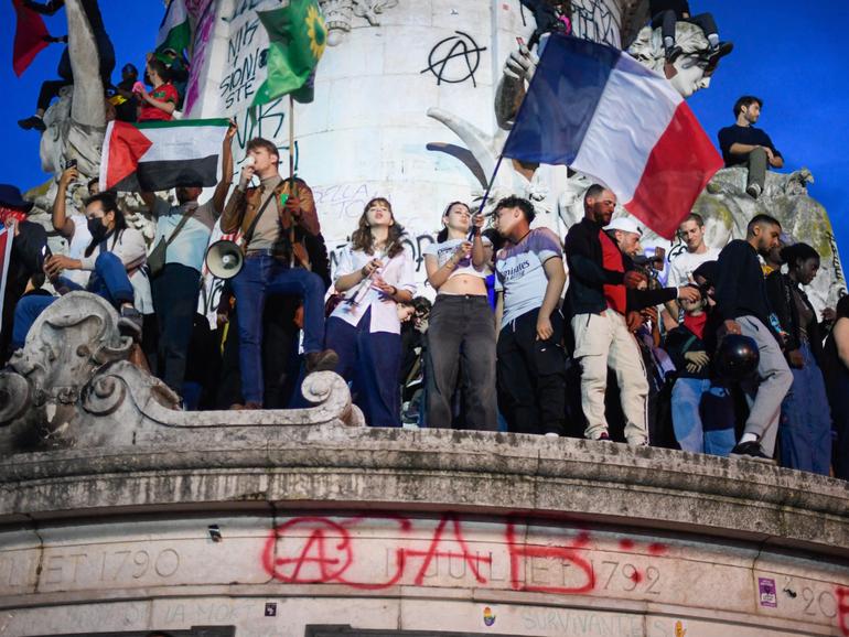 Participants gather during an election night rally following the first results of the second round of France's legislative election at Place de la Republique in Paris.