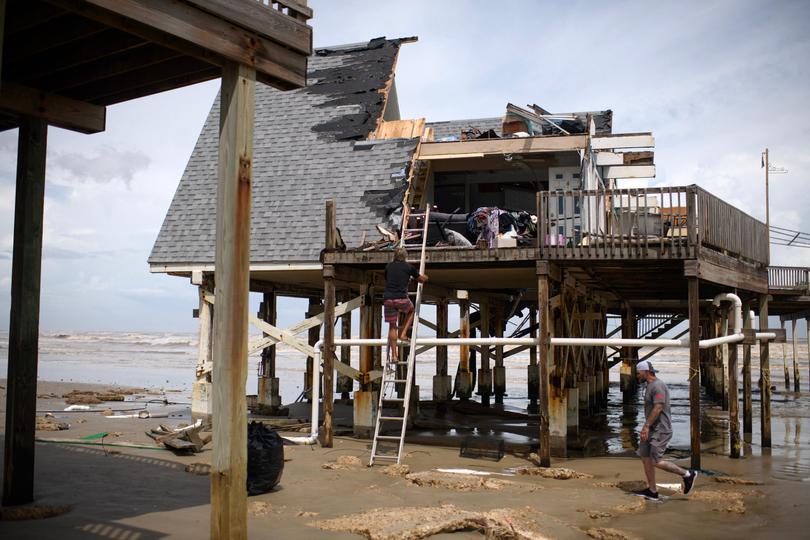 Mike Isbell climbs a ladder to look at the remains of his home which was destroyed in Surfside Beach, Texas.