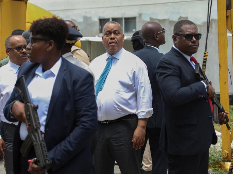 Security surrounds Haitian Prime Minister Garry Conille, centre, as he arrives at the General Hospital in Port-au-Prince.