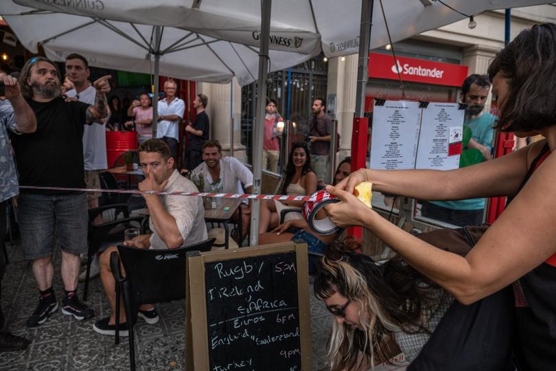 A protester is seen symbolically closing the terrace of one of the restaurants in Barceloneta, which is very popular with tourists.