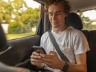 Young Man Using a Phone in the Back of a Ride Sharing Car