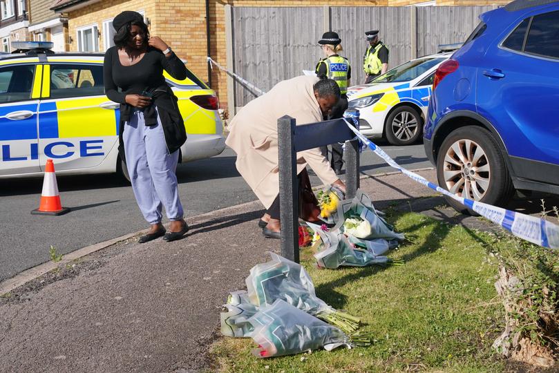 A woman delivers floral tributes near to the scene in Ashlyn Close, Bushey, Hertfordshire, where the wife and two daughters of a BBC sports commentator have been killed in a crossbow attack at their home. 