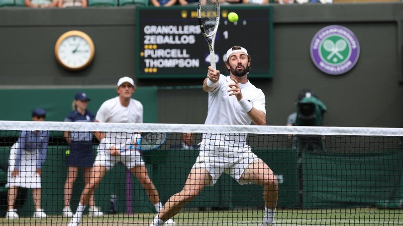 Jordan Thompson volleys with Max Purcell behind him in their men's singles semi-final Wimbledon win.