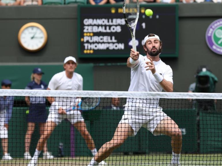 Jordan Thompson volleys with Max Purcell behind him in their men's singles semi-final Wimbledon win.