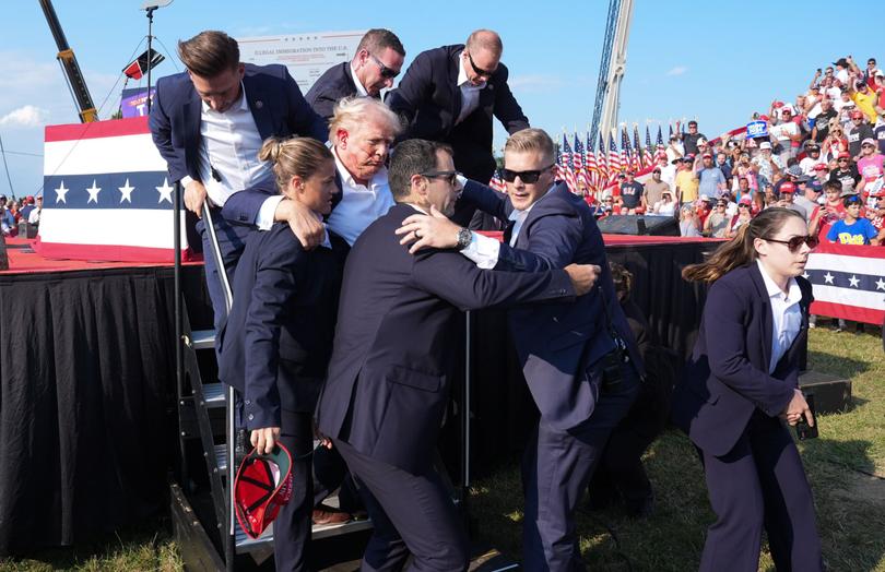 Former President Donald Trump is assisted offstage during a campaign rally in Butler, PA., on Saturday. 