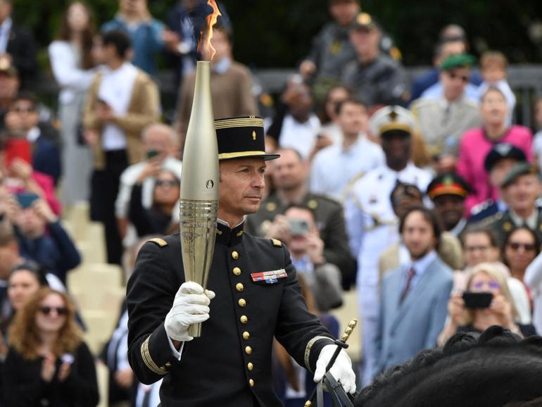 Head of the Cadre Noir de Saumur squires and gold medallist in Rio in 2016 Thibaut Vallette holds the Olympic flame torch on a horse during the Bastille Day parade.