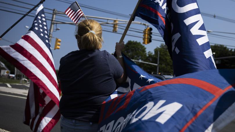 Lisa Burke of New Vernon, N.J., displays flags in support of former president Donald Trump near Trump National Golf Club in Bedminster, N.J. 