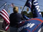 Lisa Burke of New Vernon, N.J., displays flags in support of former president Donald Trump near Trump National Golf Club in Bedminster, N.J. 