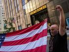 A supporter of former President Donald Trump helps to unfurl an oversized United States flag outside Trump Tower in midtown Manhattan on Sunday morning, one day after Trump was shot while speaking at a campaign rally.