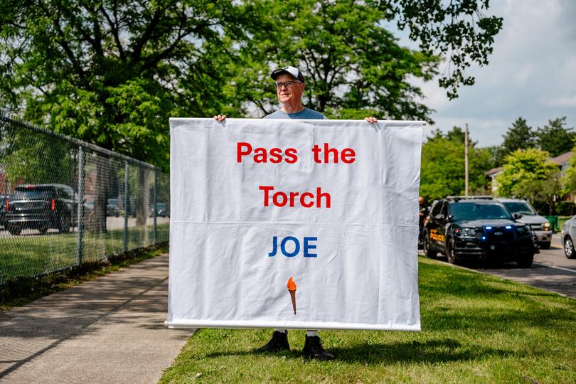 Tom Moran, 69, of Fenton, Mich., holds a sign outside Detroit’s Renaissance High School where President Biden was speaking last week. (MUST CREDIT: Nick Hagen for The Washington Post)